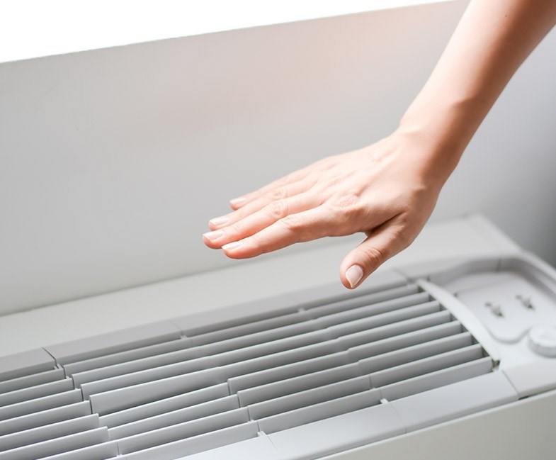 Person varmer sin hånd ved varmepumpe